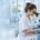 Embrióloga trabajando con un microscopio en un laboratorio de fertilidad moderno, rodeada de tecnología clínica y gráficos digitales de análisis de datos.
